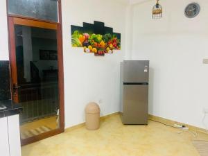 a kitchen with a refrigerator and a picture of fruits and vegetables at willow Blossoms in Pannipitiya