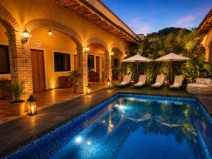 a swimming pool in a house with chairs and umbrellas at Hotel Boutique Sol y Luna SPA in Ajijic