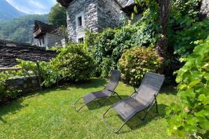 two chairs sitting in the grass next to a building at Rustico Caterina - Corippo- Happy Rentals in Corippo +16 photos