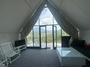 a living room with a large window and a balcony at Hummingbird St.Clare Villas in Dimbula