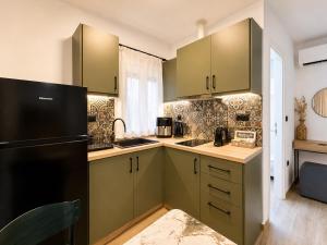a kitchen with green cabinets and a black refrigerator at Elaia & Nyx Residence in Volos