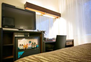 a room with a television and a desk with a bed at Hotelli Gustavelund in Tuusula