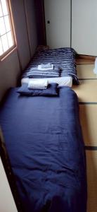 two beds in a room with blue sheets and a window at TRIANGLEosaka in Osaka