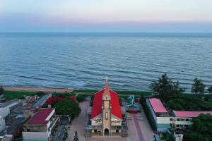 a church with a red roof next to the water at maison Ty Homestay in Phan Thiet