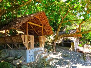 a bamboo hut with a staircase in front of a tree at L'Astrolabe - Private Beach in Baras