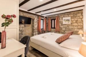 a bedroom with a large bed and a stone wall at Split Old Town Rooms Matushko in Split +27 photos