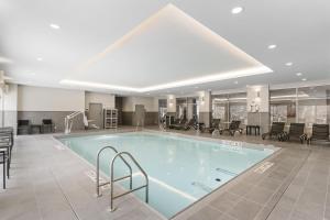 a large swimming pool in a large room with tables and chairs at Hyatt House Thunder Bay in Thunder Bay