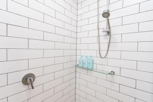 a white tiled shower with two bottles of shampoo at Rouse Hills TownCentre luxury accommodation in Kellyville +36 photos