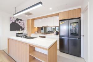 a kitchen with a stainless steel refrigerator and white cabinets at Rouse Hills TownCentre luxury accommodation in Kellyville