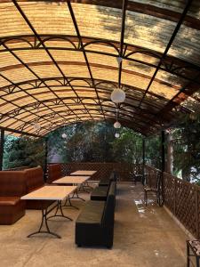 a row of tables and benches under a wooden ceiling at Green House in Karakol