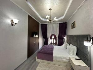 a bedroom with a bed and a chandelier at GRAND SARBON HOTEL in Qarshi