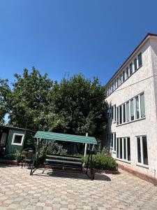 a bus stop with a bench in front of a building at Green House in Karakol