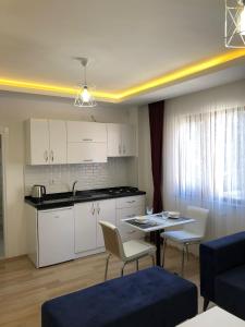a kitchen with white cabinets and a table and chairs at AiRPORT TO THE HOTEL AND HOME in Pelitli