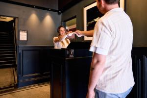 a woman brushing her teeth in a bathroom with a man at The Strand Hotel in Sydney