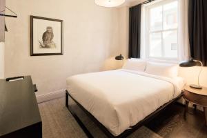 a bedroom with a bed with white sheets and a window at The Strand Hotel in Sydney +26 photos