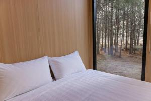 a bed with white pillows in front of a window at The Hideaway at Novena Pines by Tiny Away in Thulimbah