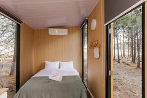 a bed in a small room with a window at The Hideaway at Novena Pines by Tiny Away in Thulimbah