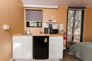 a small kitchen with a sink and a microwave at The Hideaway at Novena Pines by Tiny Away in Thulimbah +20 photos