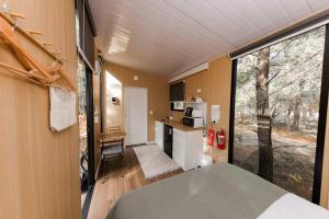 a small room with a kitchen and a large window at The Hideaway at Novena Pines by Tiny Away in Thulimbah