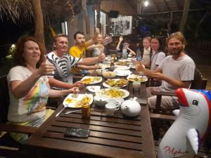 a group of people sitting around a table eating food at Whisky Point Surf Cabanas in Ampara