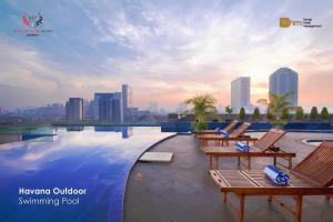 a swimming pool with chairs and a city skyline at Merlynn Park Hotel in Jakarta
