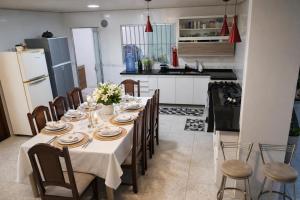a dining room with a table with chairs and a kitchen at Quarto privativo em Guriri casa de praia in São Mateus
