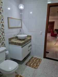 a bathroom with a white toilet and a sink at Quarto privativo em Guriri casa de praia in São Mateus +41 photos