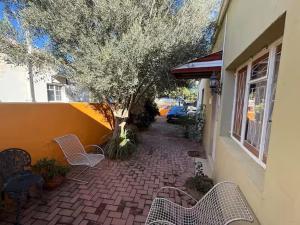 a patio with chairs and a tree next to a building at The Rose and Olive in Cradock