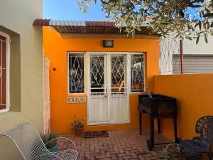an orange house with a white door and chairs at The Rose and Olive in Cradock