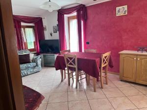 a dining room with a table and chairs and red walls at La villetta di Lilly in Predaia