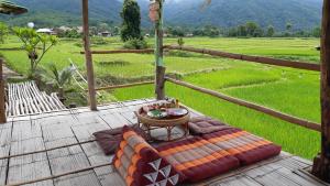 a couch on a deck with a view of a field at ชมนาโฮมสเตย์บ้านนาคำ in Ban Bun Yun +29 photos