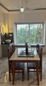 a dining room table with two chairs and a window at Malhar Homes in Kozhikode
