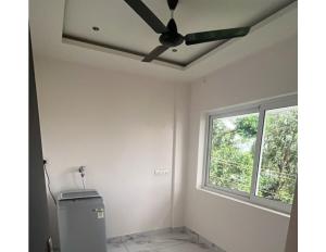 a ceiling fan in a room with a window at Malhar Homes in Kozhikode