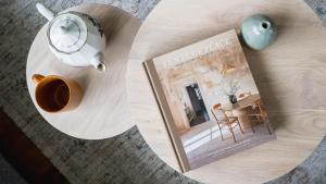 a table with a book and a cup of coffee and a table with a house at Three Oaks in Red Hill