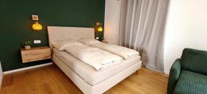 a white bed in a room with a green wall at Ferienwohnungen Meier in Ebensee