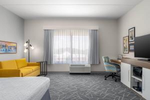 a hotel room with a bed and a couch and a desk at Hampton Inn Baltimore Bayview Campus in Baltimore