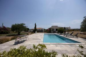 a swimming pool with two chairs and a table at Villa Helychrisa in Aléria