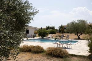 a swimming pool with chairs and a table next to it at Villa Helychrisa in Aléria