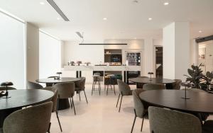 a dining room with tables and chairs and a kitchen at Hotel Ogar Tomelloso in Tomelloso