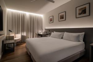 a bedroom with a large white bed and a desk at Hotel Ogar Tomelloso in Tomelloso