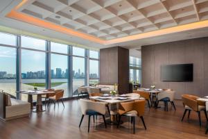 a restaurant with tables and chairs and a flat screen tv at Hilton Wenzhou in Wenzhou
