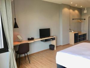 a bedroom with a bed and a desk with a television at Sans Hotel in Ban Rong Chang