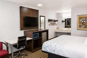 a hotel room with a bed and a desk and a television at Masters Inn Augusta at Washington Road in Augusta