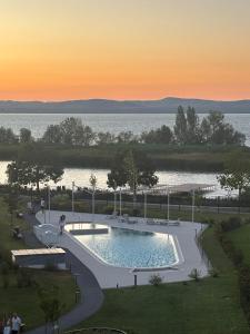 a swimming pool with a sunset in the background at Szemesbay Serenity Apartman in Balatonszemes