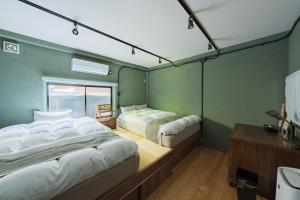 two beds in a room with green walls at 江ノ島の島内で一棟貸し一日一組限定はまさき旅館 in Fujisawa