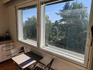 two windows in a room with a table and chairs at Sunny 4th-Floor Park-View Studio Escape in Turku