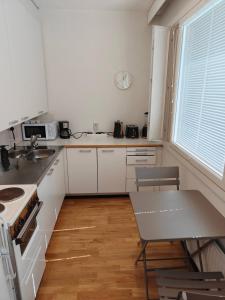 a kitchen with white cabinets and a table and a window at Sunny 4th-Floor Park-View Studio Escape in Turku +4 photos