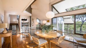 a dining room with a table and chairs and large windows at Coastal Wilderness Retreat in Hardys Bay