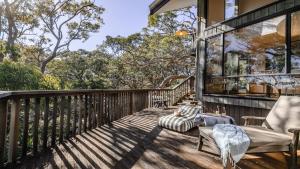 a deck with two chairs and a window at Coastal Wilderness Retreat in Hardys Bay