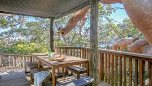 a wooden deck with a table and chairs and an elephant at Coastal Wilderness Retreat in Hardys Bay